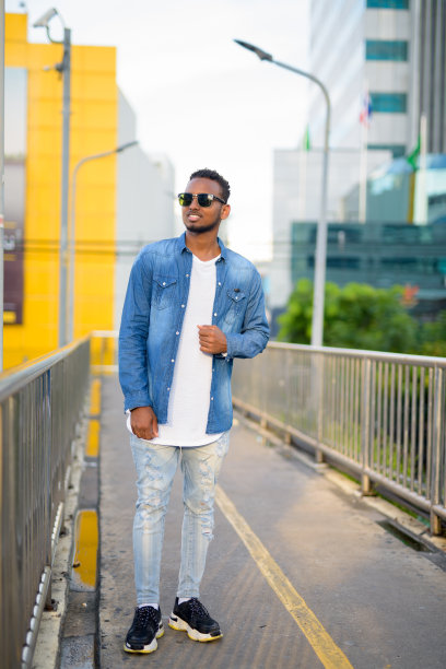 全身照片，快乐的年轻非洲人在人行桥上思考图片下载