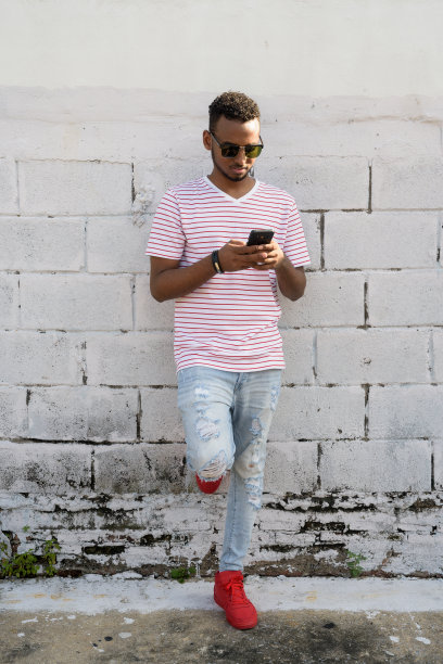 年轻非洲男子戴着太阳镜在户外打电话的全身照图片下载
