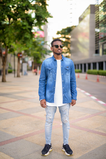 全身照片的快乐年轻非洲人戴着太阳镜在城市思考图片下载