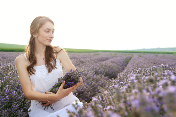 年轻的女孩在薰衣草地里捧着花束图片下载
