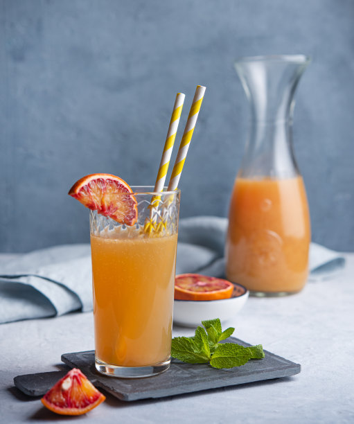 香甜的鲜榨橙汁，配上一片红橙和薄荷，背景为灰蓝色图片下载