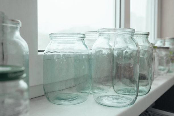 窗户附近有许多大小不一、没有盖子的空玻璃罐子。生活照片。图片下载