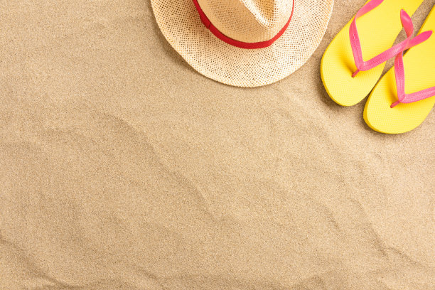沙滩背景上的拖鞋、草帽。海滩度假概念。顶部视图与复制空间。图片下载