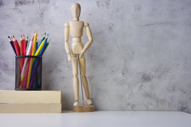 一个木制素描人物站在用蜡笔画的书旁边图片下载