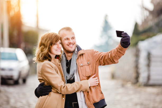 现代都市情侣在街上用智能手机拍照。图片下载
