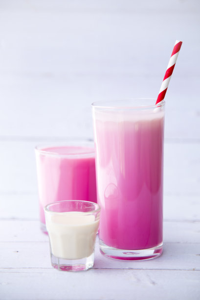 粉色草莓奶昔，高脚杯，白色木桌背景，选择性聚焦，早餐和零食的健康食品。图片下载