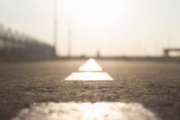 路标在地平线之外。沥青上的分界线模糊了。在明亮的阳光下为汽车和骑自行车的人准备的车道。图片下载