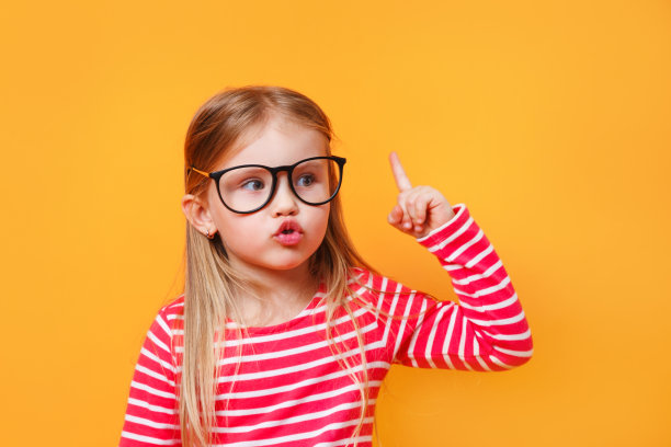 戴眼镜的小女孩惊讶地指着黄色的背景图片下载