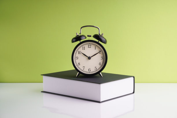 闹钟和书在绿色背景上。图片下载