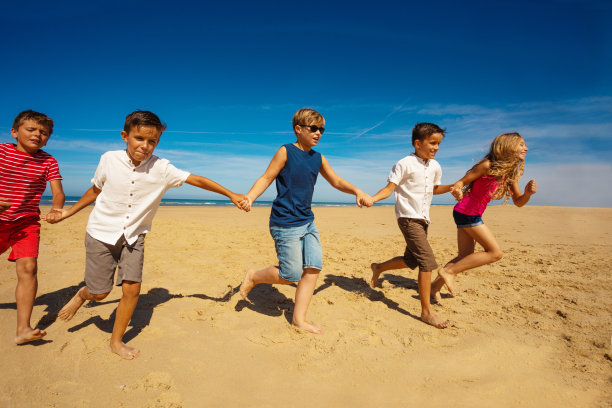 许多孩子手牵着手在沙滩上奔跑图片下载