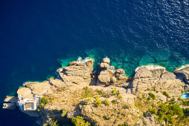 灯塔俯视图站在岩石山附近的大海与蓝色的水在波托菲诺，意大利。利古里亚的大海用巨石冲刷着海岸。图片下载