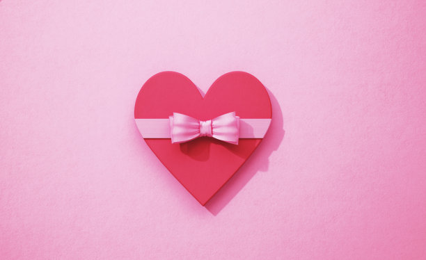 红色心形与粉红色蝴蝶结在粉红色的背景图片下载