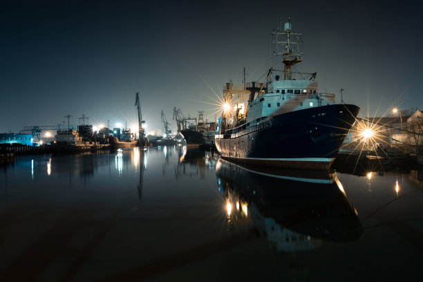 大型渔船在夜间港口与起重机的背景图片下载