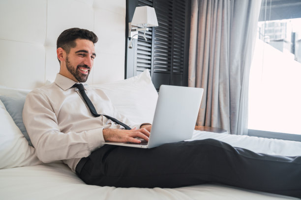 在酒店房间使用笔记本电脑的商人图片下载