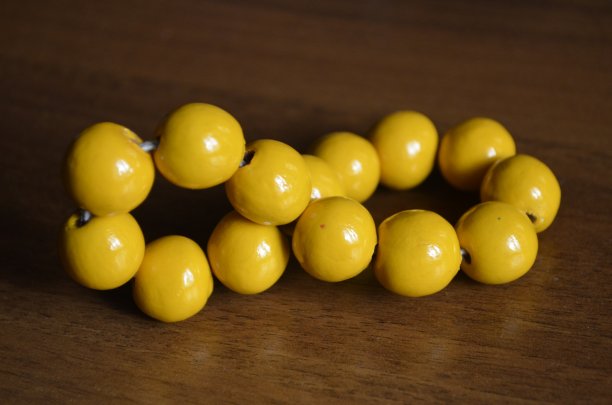 木桌上近距离放着一个带有黄色大珠子的古董手镯图片下载