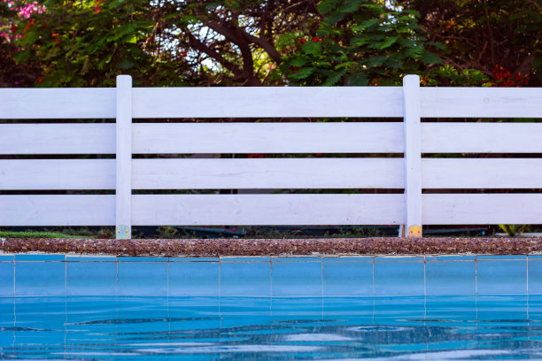 花园白色木栅栏靠近游泳池边的放松空间在后院的背景图片图片下载