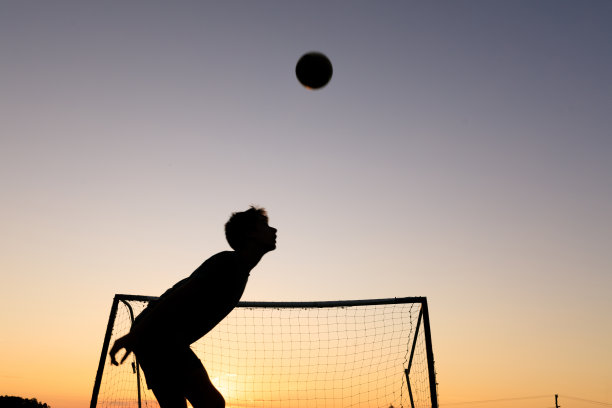 男孩在日落时练习足球技巧图片下载