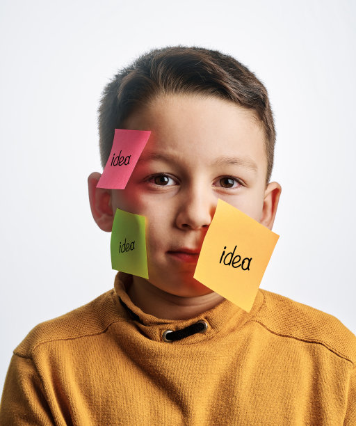 可爱的孩子在白色的背景。他的脸上有不干胶笔记。图片下载