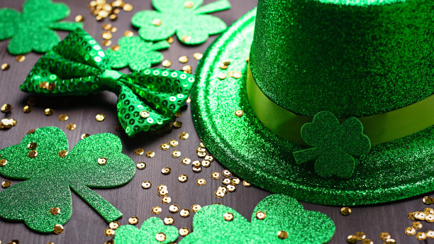 圣帕特里克节贺卡，带有传统符号，三叶草，绿色服装。绿色的帽子，领结，圣帕特里克节三叶草，金色的纸屑在深色的木制背景，复制空间图片下载