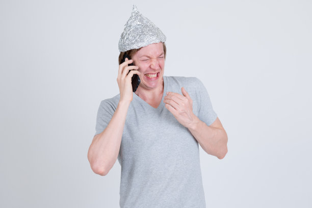一个戴着锡纸帽的紧张的年轻人在打电话，看起来很害怕图片下载