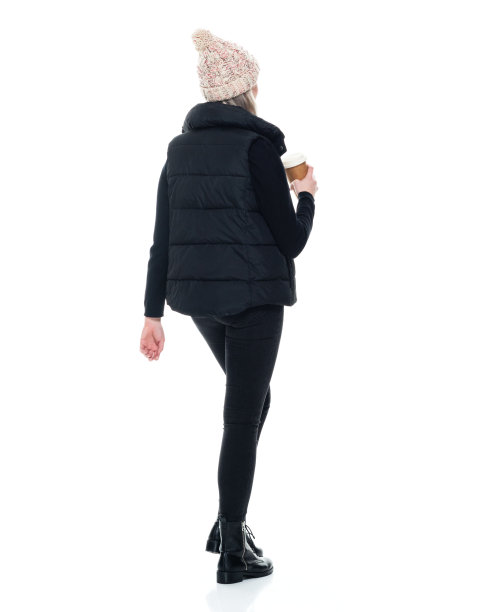 白种年轻女子身穿马甲，手持咖啡杯，无袖走在白色背景前图片下载