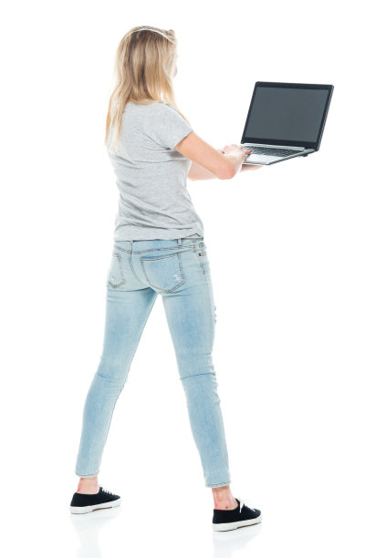z一代年轻女性穿着牛仔裤站在白色背景前使用电脑图片下载