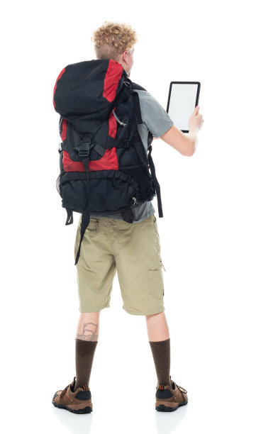 白人男性背包客穿着t恤，拿着包，用触摸屏在白色背景前徒步旅行图片下载