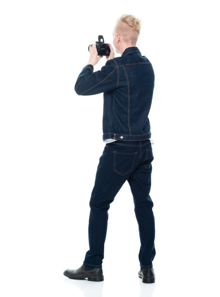 白人年轻男性摄影师站在白色背景穿着双牛仔和拿着相机图片下载