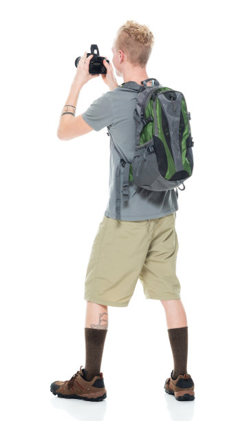 白人年轻男性摄影师徒步旅行在白色背景下，背着背包和拿着相机图片下载