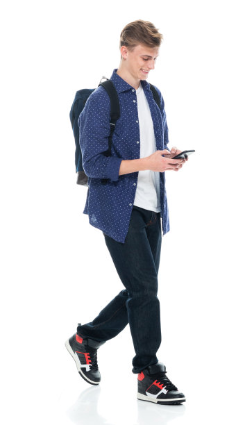 男生背着书包，拿着课本，用手机走在白色背景前图片下载