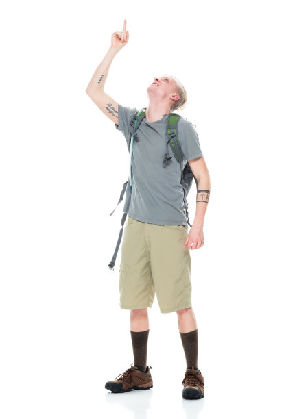 白人年轻男性背包客在白色背景下背着背包和拿着包徒步旅行图片下载