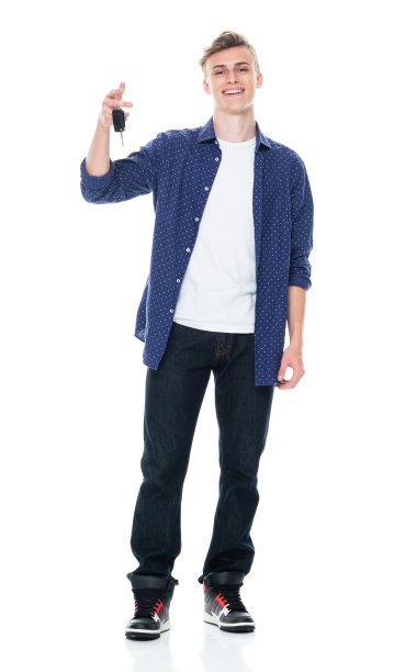 白人十几岁的男孩汽车销售员站在前面的白色背景穿着裤子和拿着钥匙图片下载