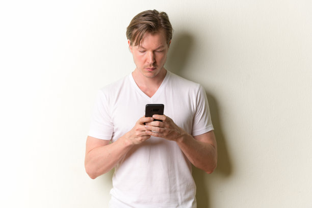 年轻英俊的长头发男子的肖像使用电话图片下载