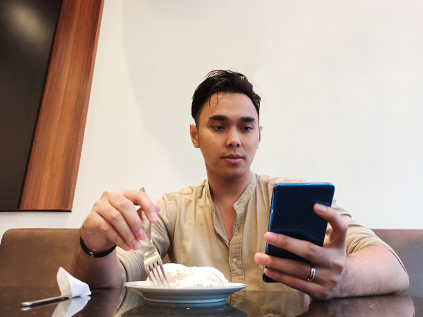 亚洲男人一边吃一边玩智能手机图片下载