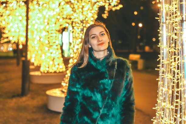 在明亮的背景下，年轻漂亮的女孩穿着绿色毛皮大衣图片下载