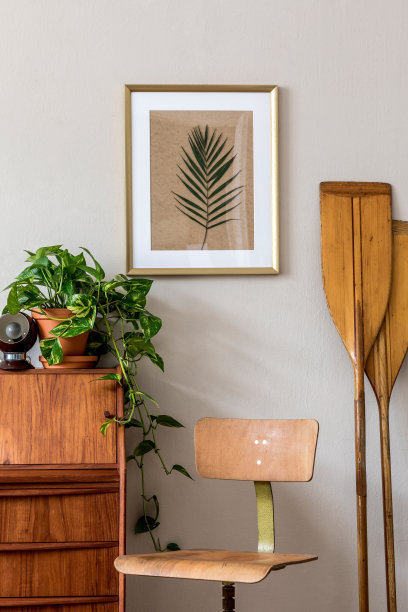 时尚和复古的室内设计的客厅与木制复古的马桶和椅子，植物，桨和优雅的个人配件。把海报画框挂在墙上。模板。家居装饰。图片下载