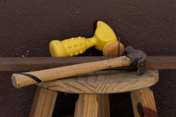 木板上旧金属锤旁边的黄色玩具锤图片下载