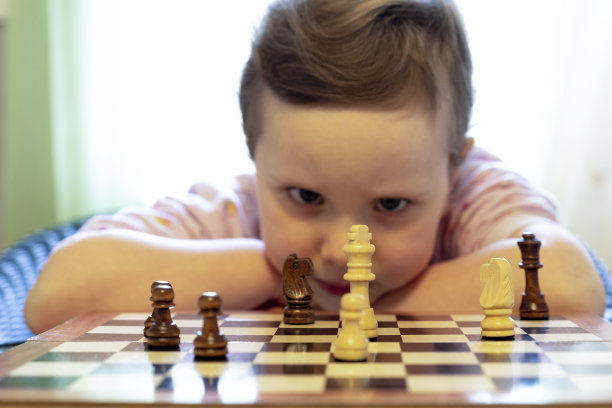 一个四岁的小女孩，若有所思地看着棋子。图片下载