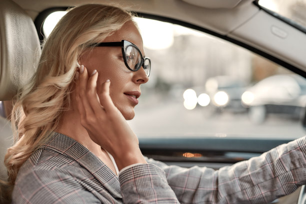 与客户交谈。肖像迷人的女人在眼镜调整耳机驾驶汽车图片下载