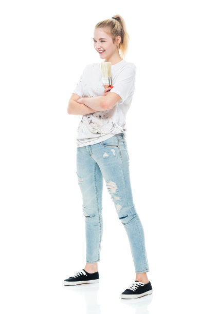 z一代年轻女性画家站着，穿着牛仔裤，拿着画笔图片下载