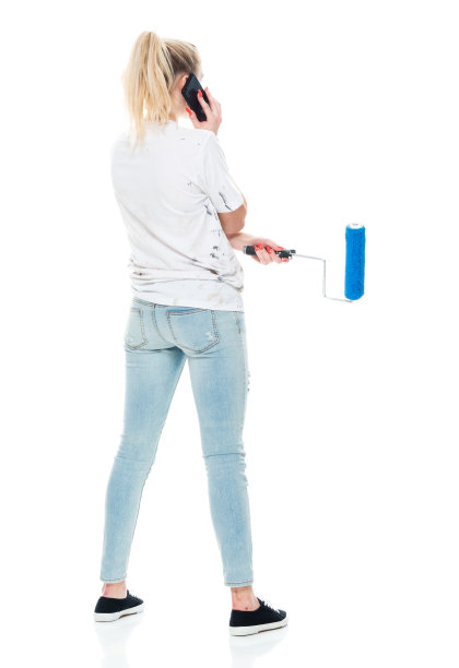 z一代少女画家穿着牛仔裤站在白色背景前使用手机图片下载