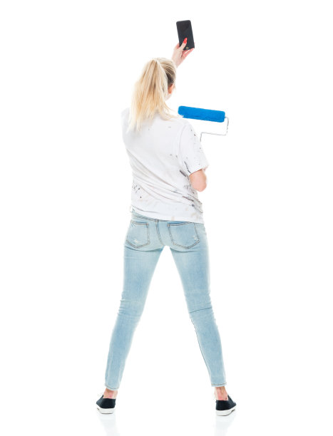 白人年轻女性穿着帆布鞋，用智能手机站在白色背景前拍照图片下载
