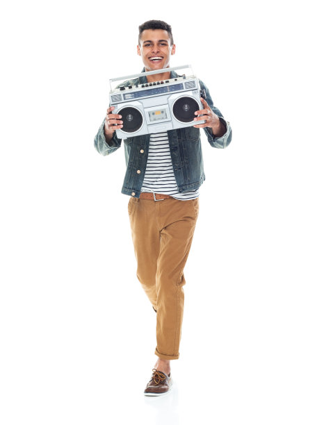 非裔美籍年轻男性舞者穿着牛仔夹克，手持立体声音响在白色背景前跳舞图片下载