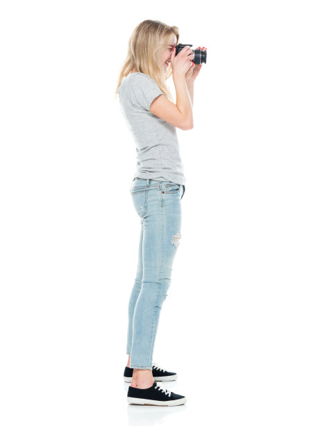 白人女游客站着，穿着帆布鞋，拿着相机图片下载