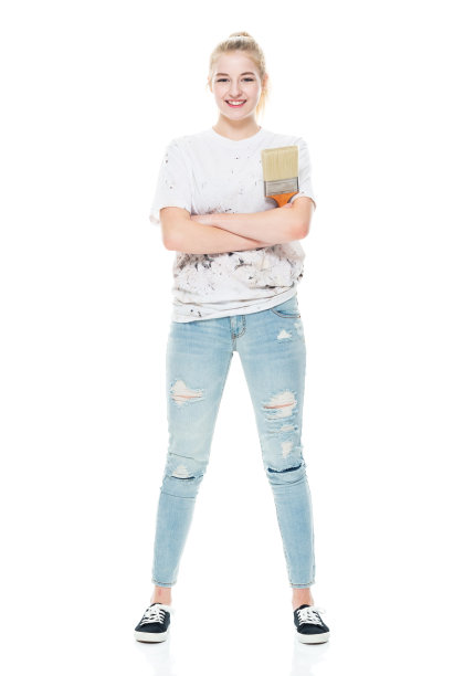 白人女油漆工站着，穿着帆布鞋，拿着画笔图片下载