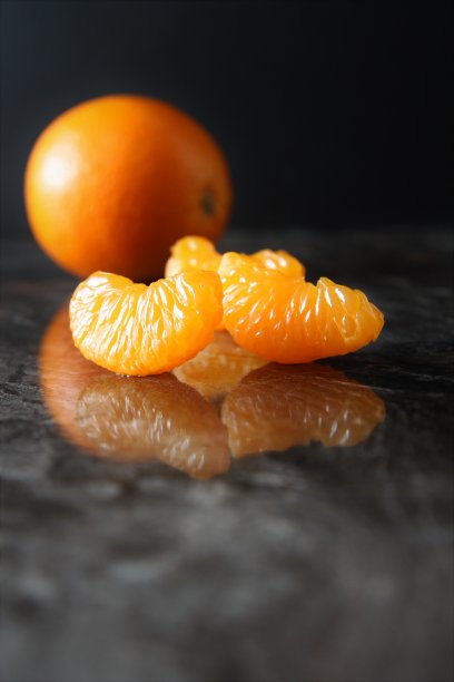 明亮的橙色多汁的桔子片上的黑色背景壮观的背景图片下载