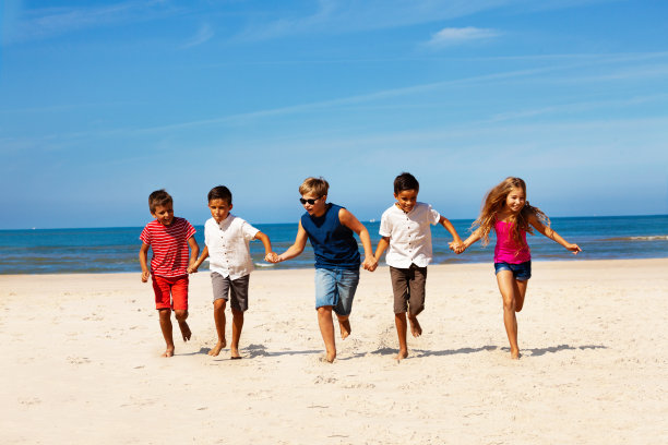 许多孩子手拉手在海滩上奔跑图片下载