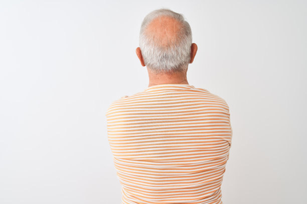 白发老人身穿条纹t恤，站在孤立的白色背景下，向后看，双臂交叉图片下载