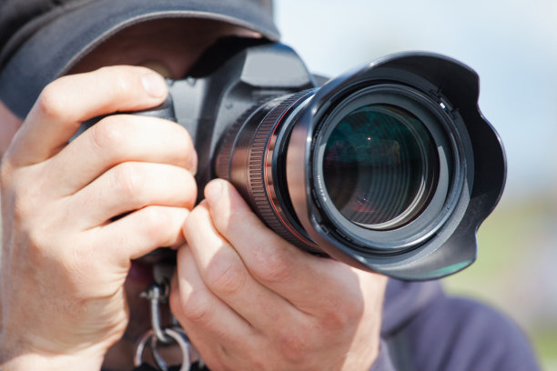 男性摄影师用一个大的专业相机看着取景器拍摄照片图片下载