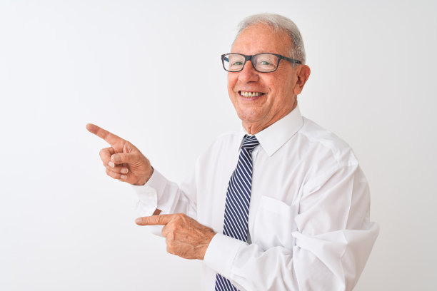 白发苍苍的资深商人戴着领带和眼镜，在孤立的白色背景下微笑着看着镜头，双手和手指指向一边。图片下载